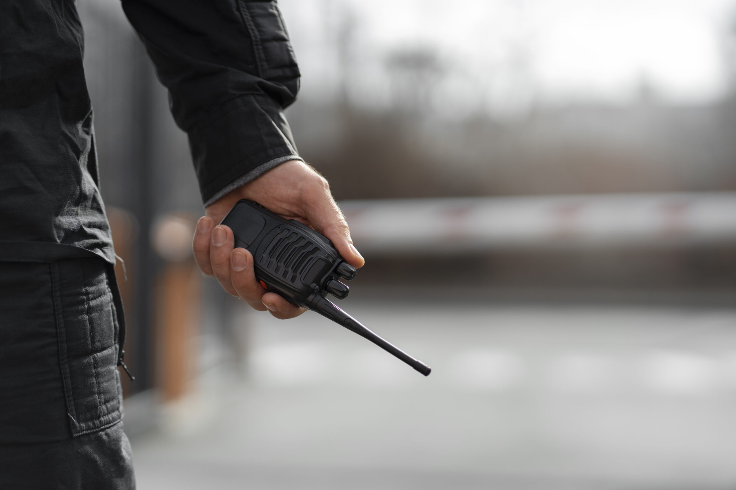 Agent Pro Tech 12 en surveillance avec talkie-walkie à Villefranche-de-Rouergue devant une barrière de sécurité,