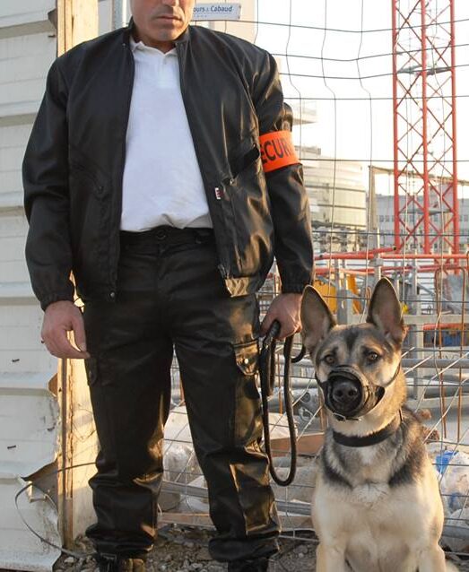 Agent Pro Tech 12 avec chien de garde sur un chantier à Villefranche-de-Rouergue devant une clôture métallique,