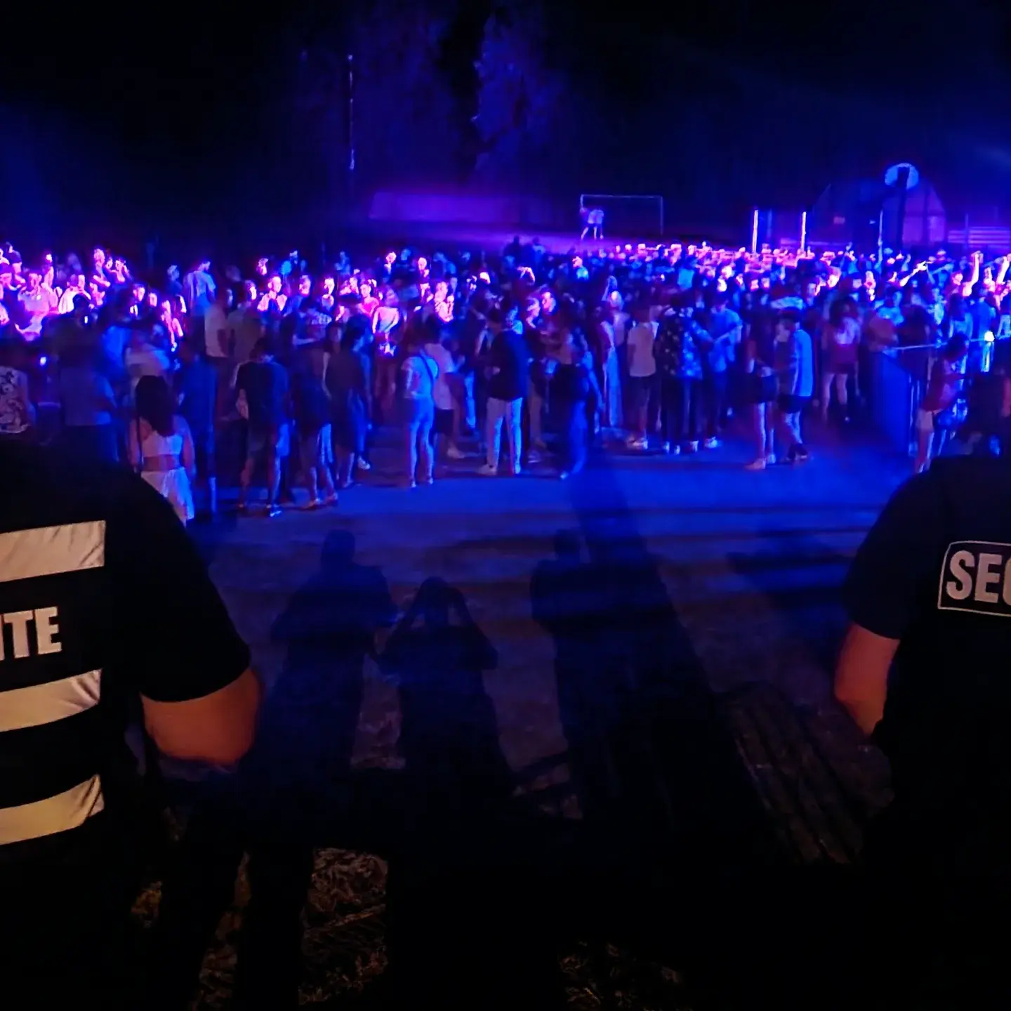 Agents de sécurité Pro Tech 12 surveillant une foule en soirée à Villefranche-de-Rouergue sous éclairages bleus,